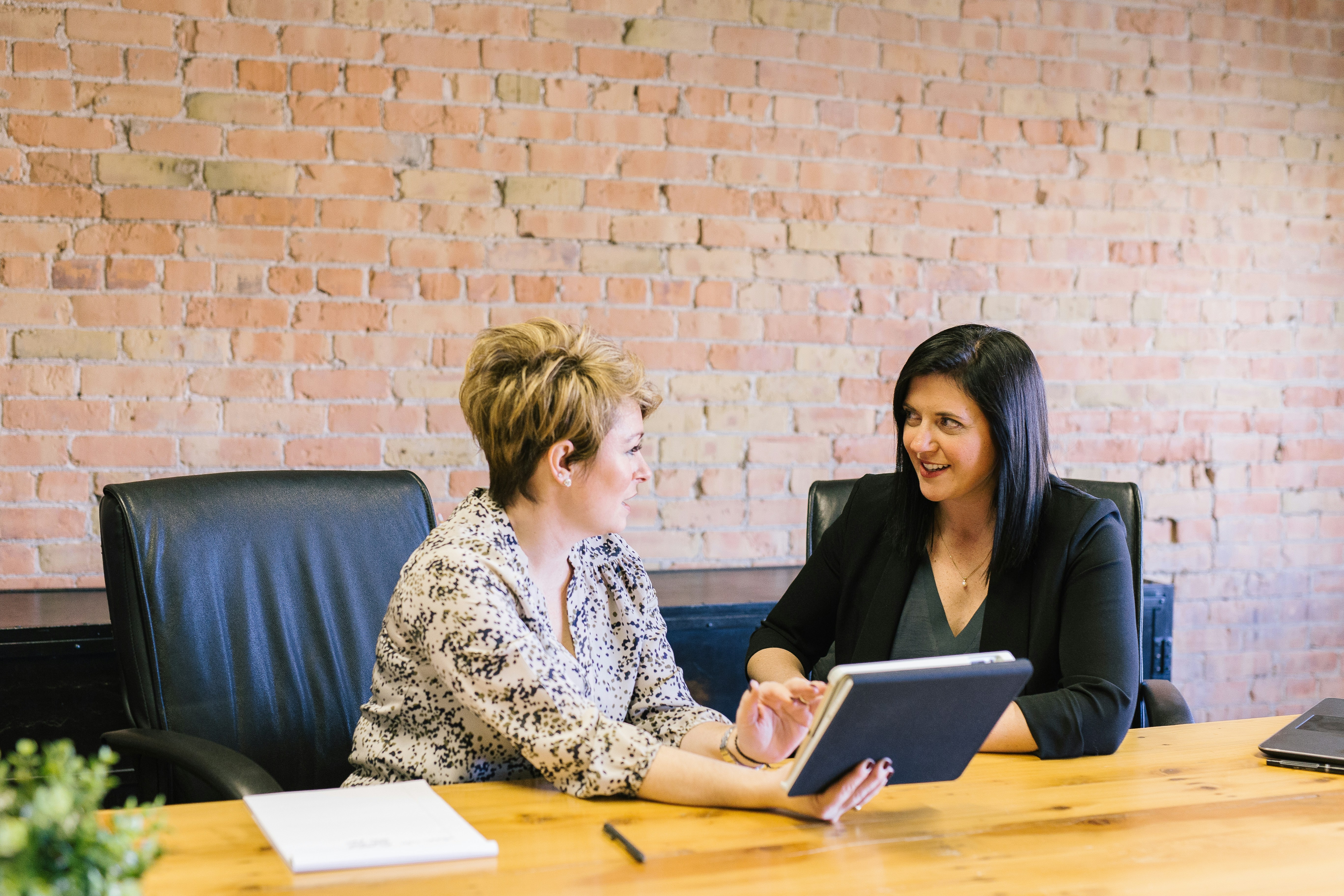 Two women meeting, looking at the same electronic tablet